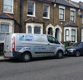 Investigating blocked drain gully at rear of property in Alloa Road, Surrey Quays, Rotherhithe SE8